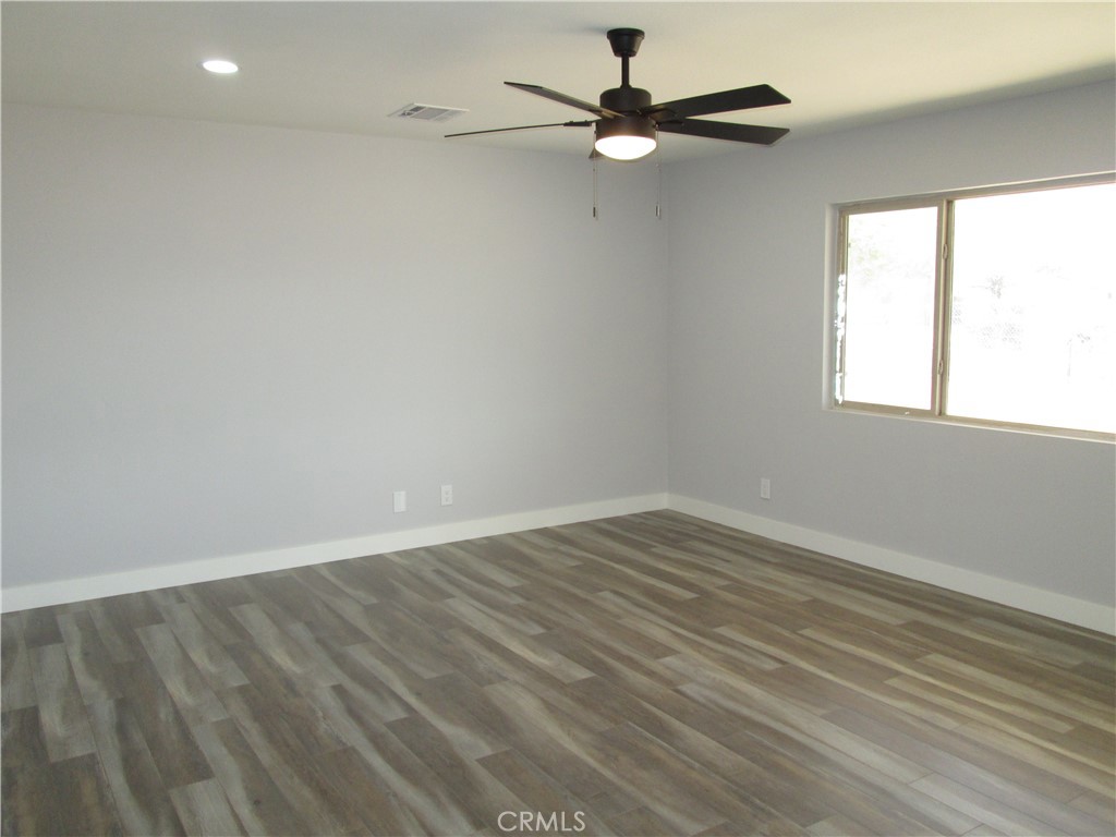 13464 Mohawk Road Apple Valley, CA 92308 - Photo 18 of 35 an empty room with wooden floor fan and windows