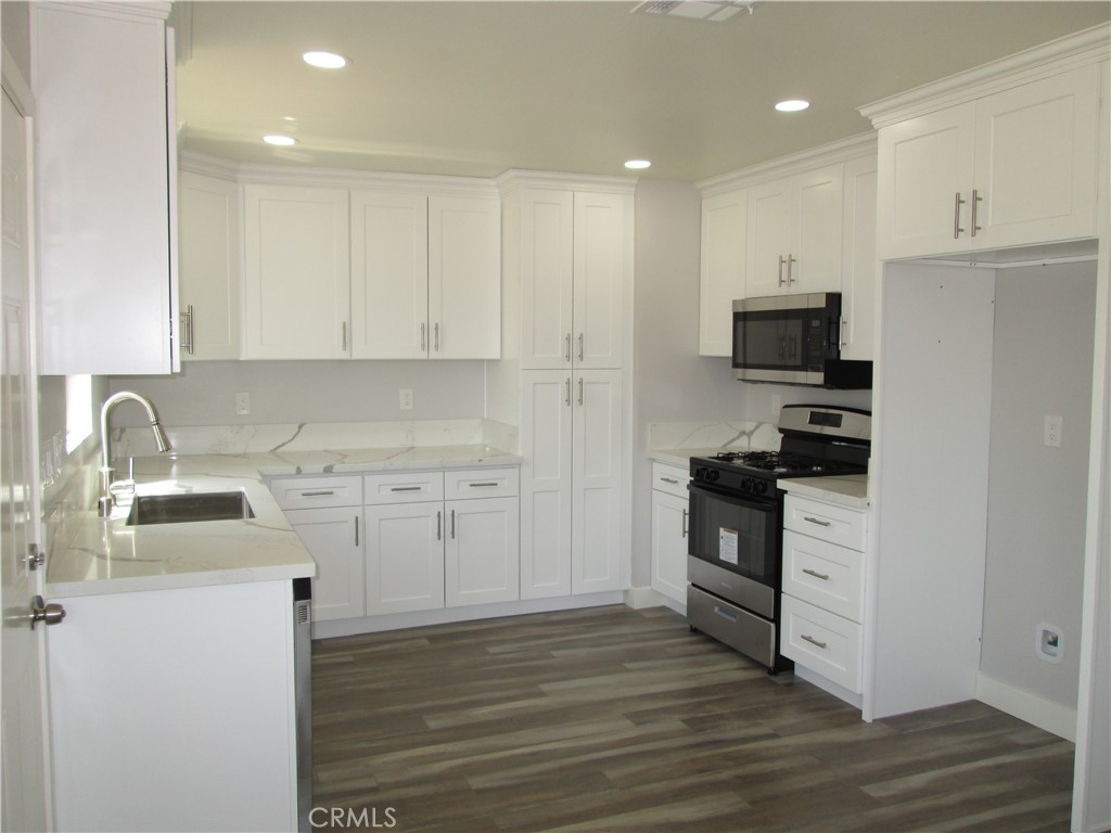 13464 Mohawk Road Apple Valley, CA 92308 - Photo 3 of 35 a kitchen with stainless steel appliances granite countertop a stove top oven a sink and white cabinets