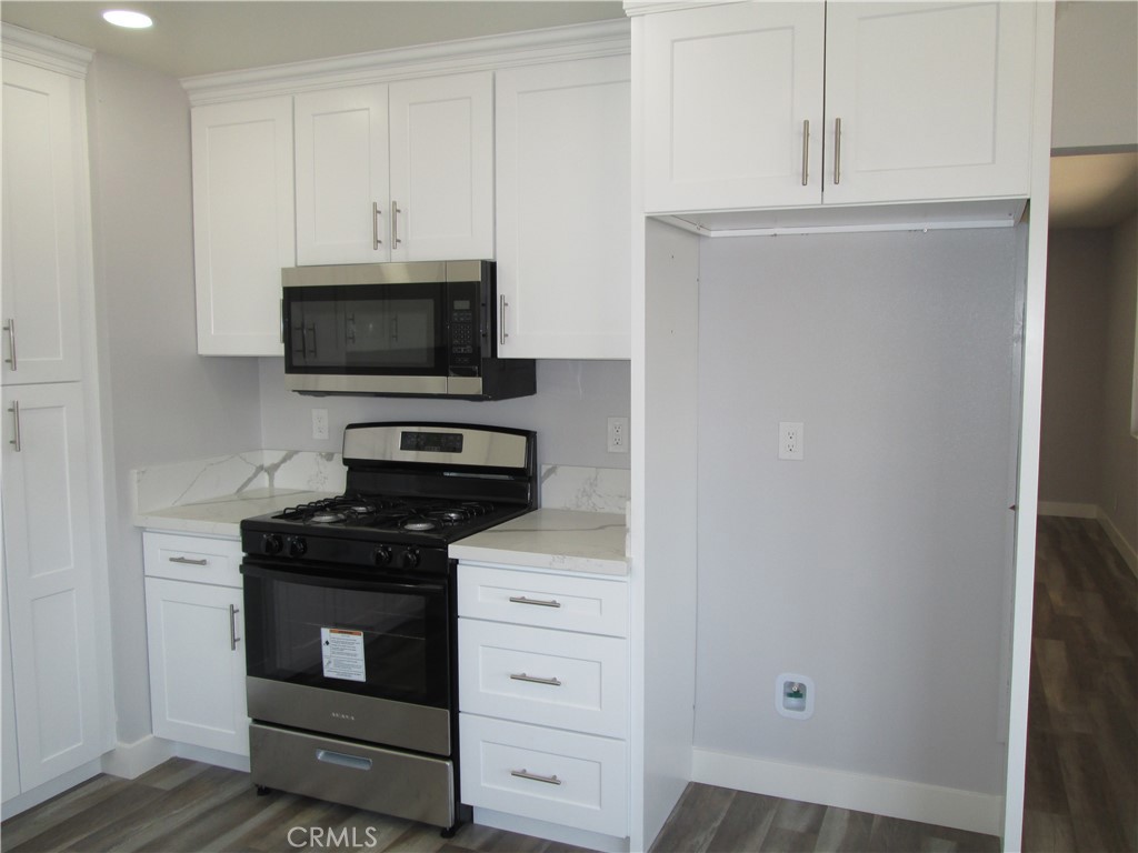 13464 Mohawk Road Apple Valley, CA 92308 - Photo 6 of 35 a kitchen with white cabinets and stainless steel appliances