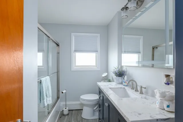 a bathroom with a granite countertop sink toilet and mirror