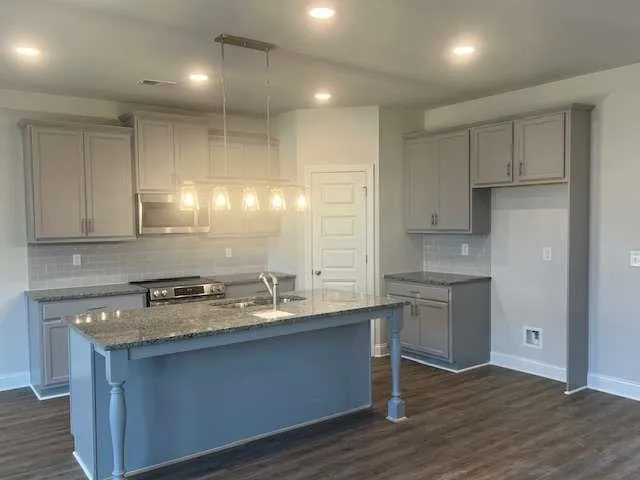 a kitchen with kitchen island granite countertop a sink cabinets and wooden floor