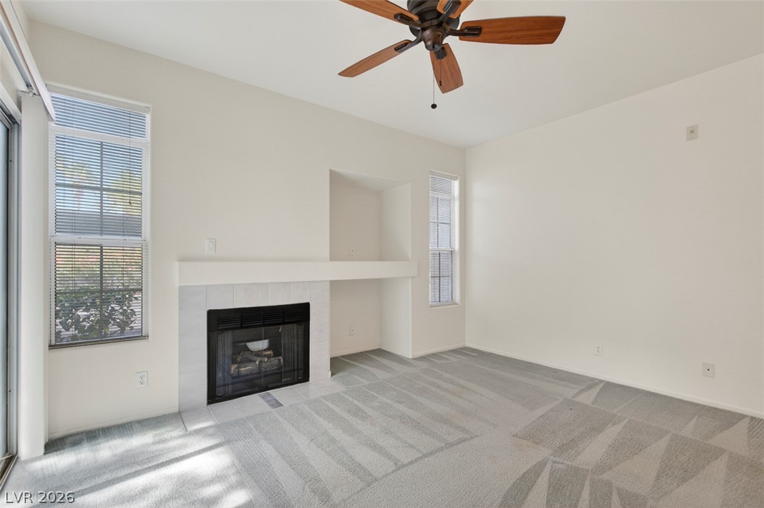2201 Ramsgate Drive, Unit 1011 Henderson, NV 89074 - Photo 5 of 40 A well-lit living space features a cozy fireplace, soft carpeting, and abundant natural light from multiple windows.