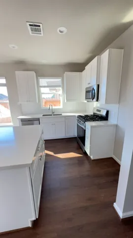 a kitchen with stainless steel appliances a sink cabinets and wooden floor
