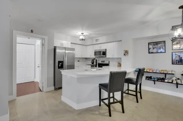 a kitchen with stainless steel appliances kitchen island a refrigerator and a dining table