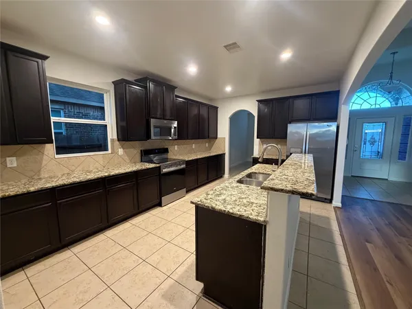 a large kitchen with stainless steel appliances kitchen island granite countertop a sink and cabinets