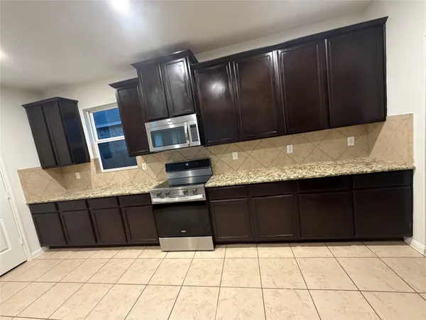 a kitchen with granite countertop wooden cabinets and black appliances