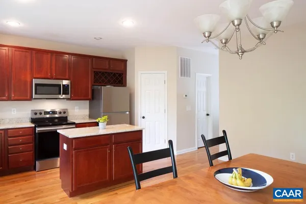 a kitchen with stainless steel appliances kitchen island granite countertop a sink dishwasher a stove a refrigerator a microwave oven with cabinets and wooden floor