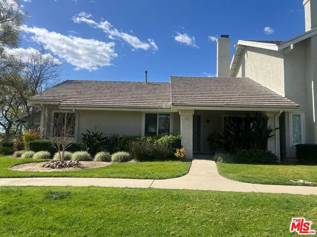 a front view of a house with a yard and potted plants
