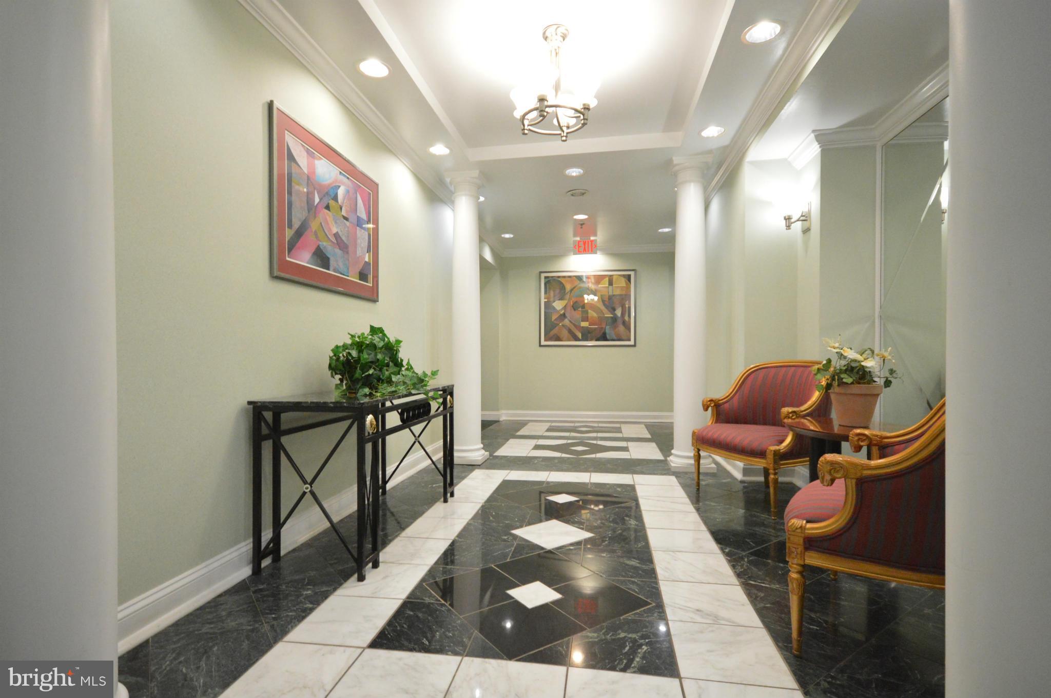 5575 Seminary Road, Unit 311 Falls Church, VA 22041 - Photo 4 of 30 a hallway with a dining table and paintings on the wall