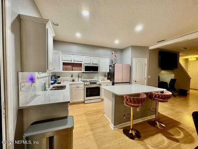 8852 Inlet Bluff Drive Jacksonville, FL 32216 - Photo 18 of 53 a kitchen with a refrigerator a stove top oven a sink dishwasher and white cabinets with wooden floor