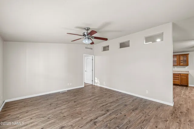 a view of a room with wooden floor and a ceiling fan