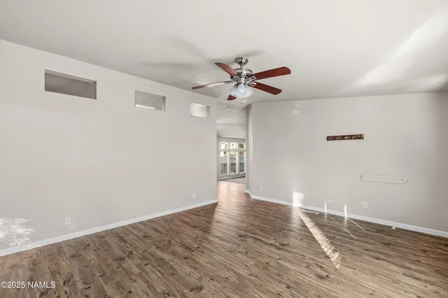 a view of an empty room with window and wooden floor
