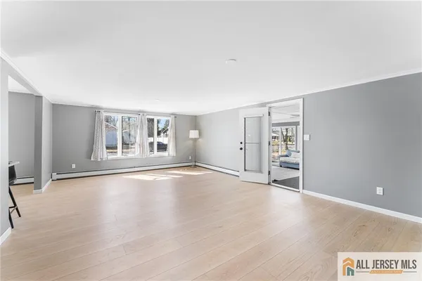a view of an empty room with window and wooden floor