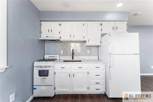 a kitchen with cabinets appliances and wooden floor