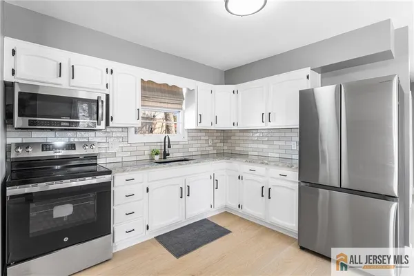 a kitchen with granite countertop a refrigerator stove and microwave