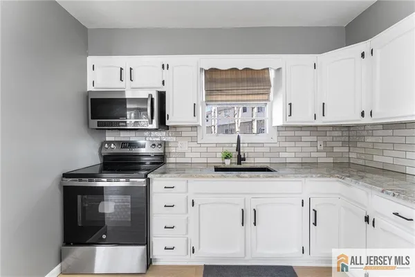 a kitchen with granite countertop white cabinets and stainless steel appliances