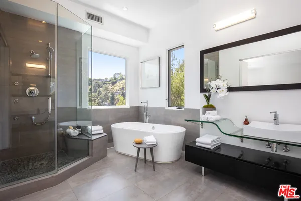 a bathroom with a double vanity sink a toilet a mirror and shower