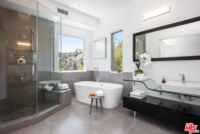 a bathroom with a double vanity sink a toilet a mirror and shower