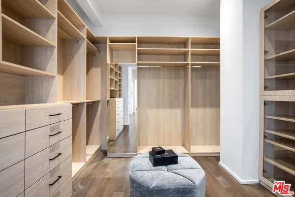 a view of walk in closet with clothes and shoes