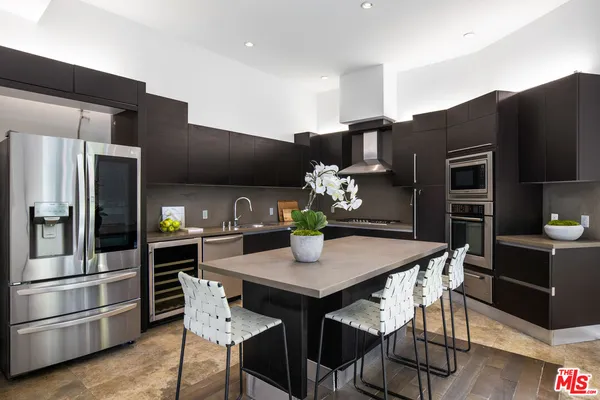 a kitchen with stainless steel appliances a dining table chairs and refrigerator