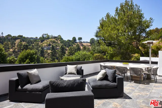 a roof deck with couches and wooden fence