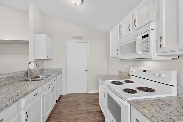 a kitchen with granite countertop white cabinets and appliances