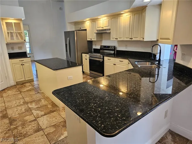 a kitchen with stainless steel appliances granite countertop a sink stove and refrigerator