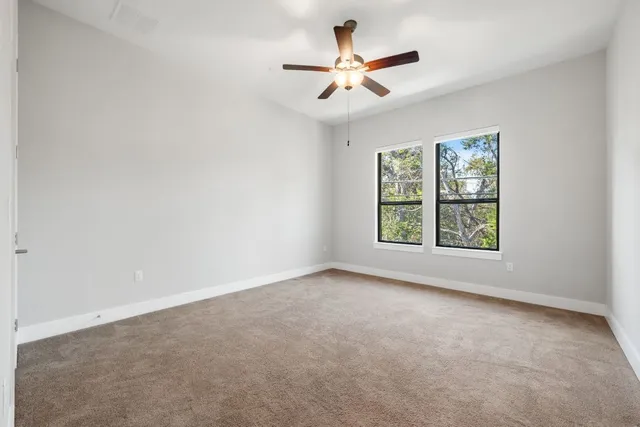 an empty room with windows and ceiling fan