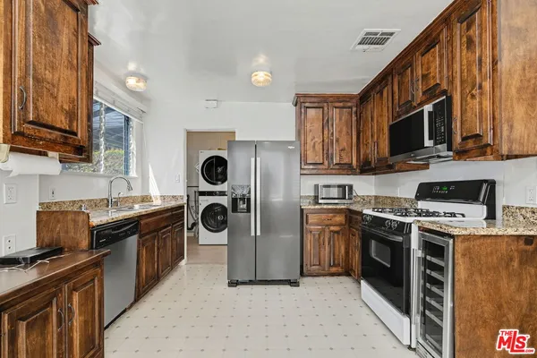a kitchen with stainless steel appliances granite countertop a stove top oven a sink dishwasher a refrigerator and a cabinets