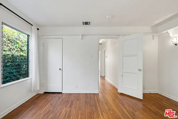 a view of an empty room with wooden floor and a window