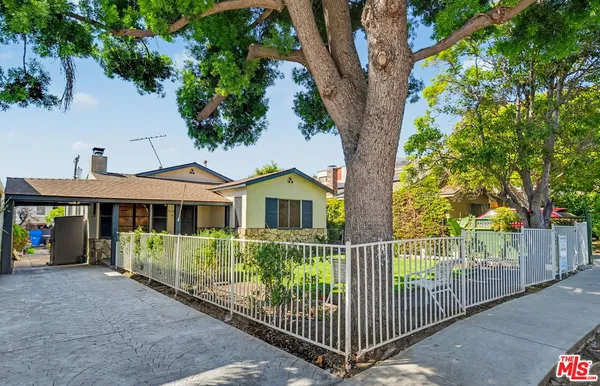 a view of a house with a small yard and a large tree