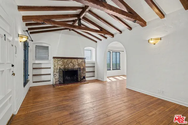 a view of an empty room with wooden floor fireplace and a window