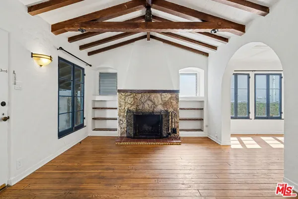 a view of a livingroom with wooden floor a fireplace and windows