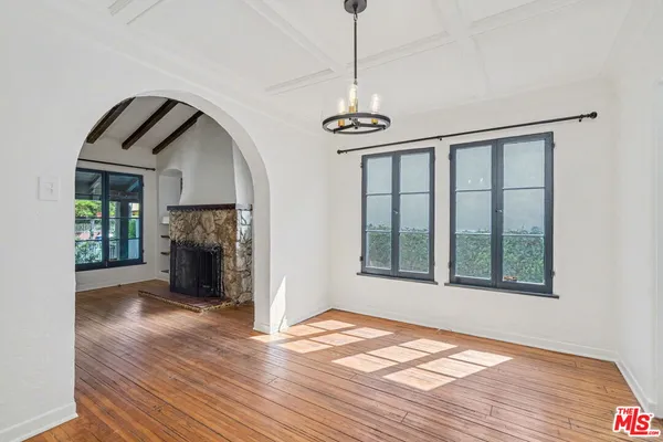a view of an empty room with wooden floor fireplace and a window