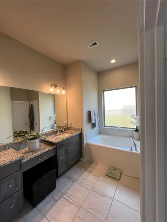 a bathroom with a tub sink and mirror