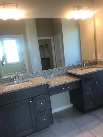 a bathroom with a granite countertop sink double and mirror