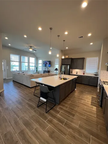 a living room with stainless steel appliances lots of furniture and kitchen view