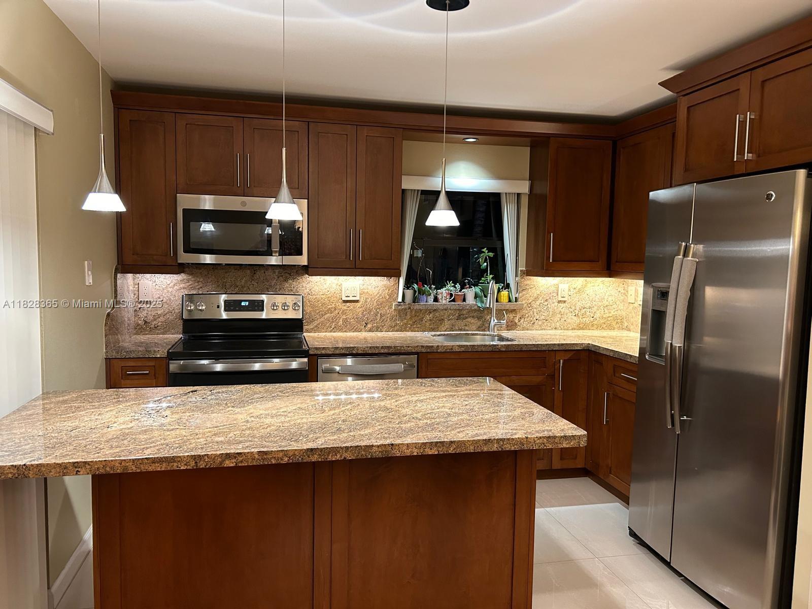 Kendale Lakes Miami, FL 33183 - Photo 3 of 12 a kitchen with stainless steel appliances wooden cabinets a sink and a refrigerator