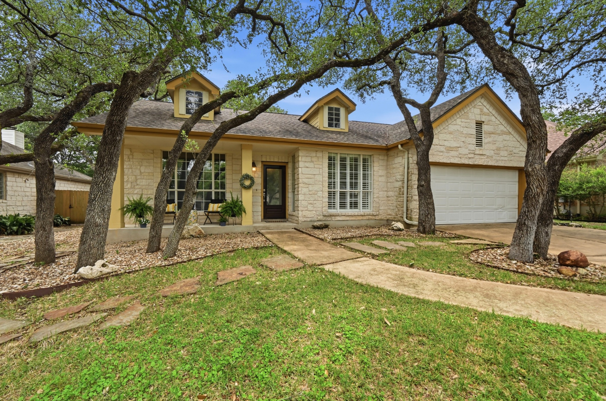 5313 Moon Shadow Drive Austin, TX 78735 - Photo 1 of 30 Stone facade home featuring a two-car garage, dormer windows, and a concrete pathway with stepping stones