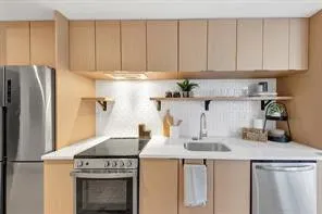 a kitchen with stainless steel appliances granite countertop a refrigerator a stove a sink and white cabinets
