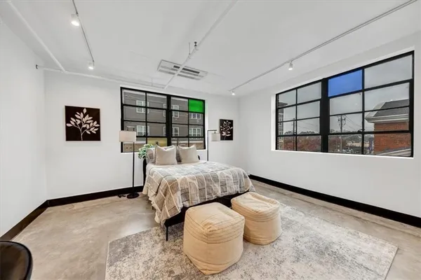 a spacious bedroom with a bed and wooden floor