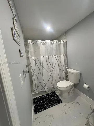 a bathroom with a toilet and a shower curtain