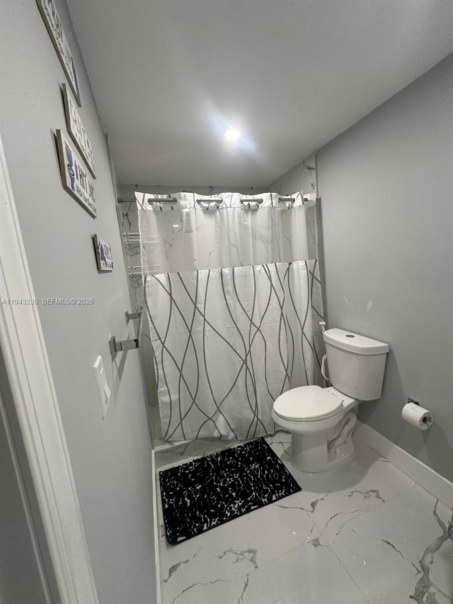 11879 Southwest 253rd Terrace Homestead, FL 33032 - Photo 2 of 15 a bathroom with a toilet and a shower curtain