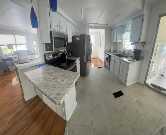a kitchen with stainless steel appliances granite countertop a stove top oven a sink dishwasher a refrigerator and white cabinets with wooden floor