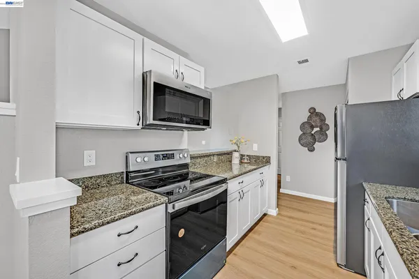 a kitchen with stainless steel appliances granite countertop a stove a sink and a microwave