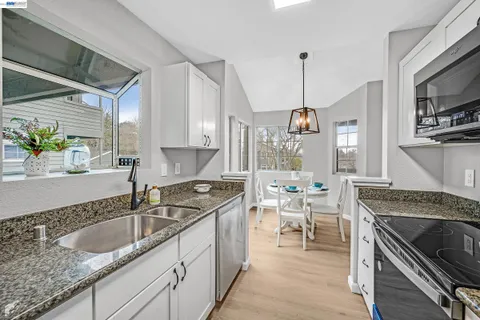 a kitchen with granite countertop a sink stove and cabinets