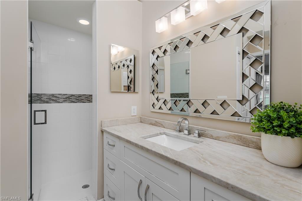 6658 Castlelawn Place, Unit 9 Naples, FL 34113 - Photo 20 of 38 Vanity with a white shaker-style cabinet, integrated sink, and light-toned countertop