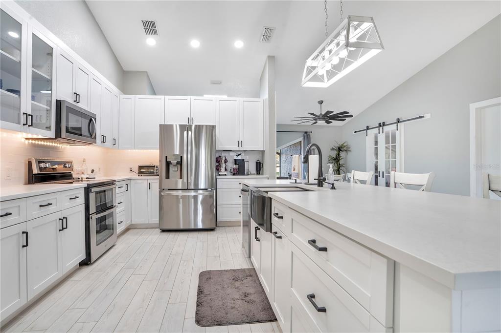 8431 Delaware Drive Weeki Wachee, FL 34607 - Photo 12 of 64 a kitchen with kitchen island granite countertop a sink cabinets and stainless steel appliances