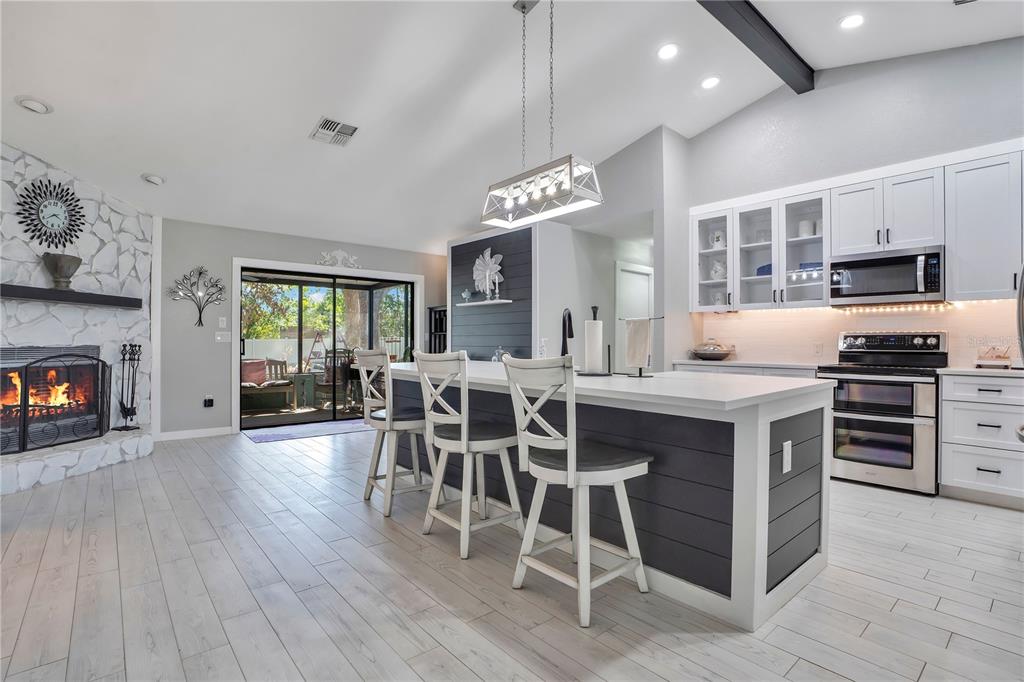 8431 Delaware Drive Weeki Wachee, FL 34607 - Photo 5 of 64 a kitchen with stainless steel appliances granite countertop a stove top oven a sink dishwasher a dining table and chairs with wooden floor