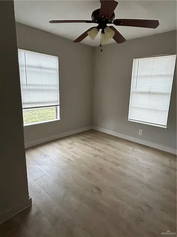an empty room with windows and fan
